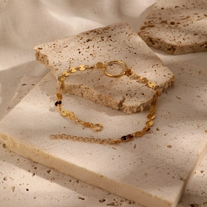 Minimalist gold 925 sterling silver bracelet with discs and ring on beige stones