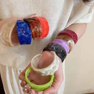 Detail of stacked colorful acrylic resin bangles with ripple texture on model arm