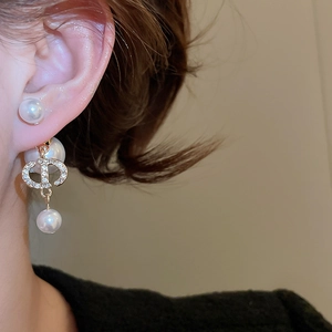 Detailed view of gold plated CD logo earrings with elegant pearls and zircon stones