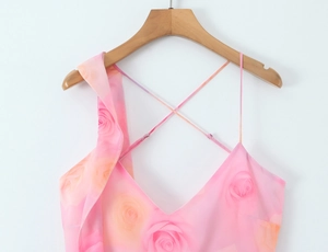 Detail of pink floral dress featuring rose print, V-neck, and delicate ruffle trim