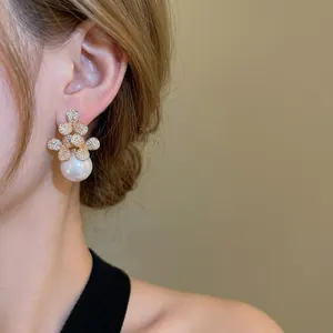 Elegant floral pearl drop earrings with zircon crystals shown on a female model