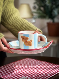 Close-up of hand holding a dog ceramic coffee cup with blue stripes and red rim