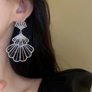 Close-up of fan-shaped silver earrings with sparkling crystals worn by a model