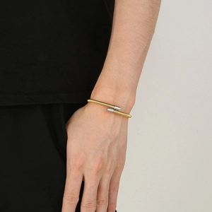 Two-tone silver and gold twisted cable stainless steel bangle with anchor design on model