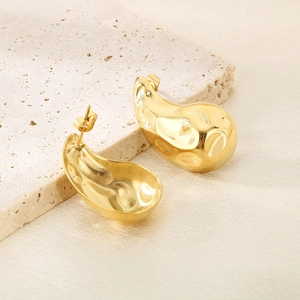 Detailed view of gold irregular liquid metal earrings on textured stone base