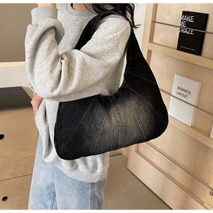 Détail du sac bandoulière en denim noir avec design patchwork vintage tenu par un modèle