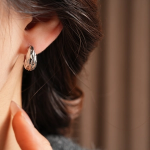 Detailed view of silver faceted teardrop earring worn on ear with high-end polished finish