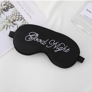 Detail of black silk sleep mask with white Good Night embroidery and adjustable strap
