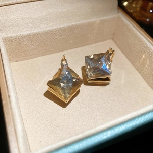 Detailed macro view of diamond-cut rhombic crystal earrings in a gold setting