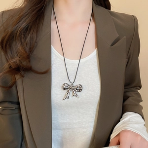 Close-up of a leopard print bow pendant necklace on a model wearing a brown blazer