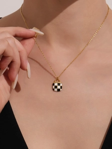 Macro shot of gold stainless steel necklace with black and white checkered pendant