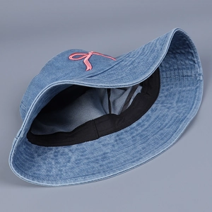 Detail der rosa Schleifenstickerei auf blauem Denim-Stoff mit schwarzem Schweißband