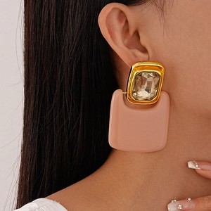 Detailed close-up of a large geometric resin earring with champagne stone on a female model