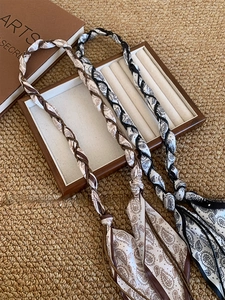 Détail d'une ceinture en foulard de soie bohème avec perles sur un plateau en bois