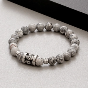 Detail view of 8mm marble textured stone beads and a carved metal skull charm bracelet