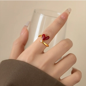 Detailed close-up of 18k gold heart ring with red enamel and sparkling zircon stone