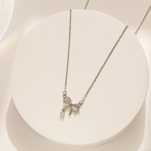 Detailed macro view of silver bow pendant with cat eye wings and round zircon stone