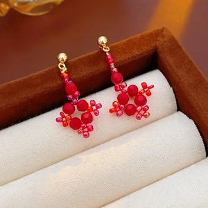 Macro shot of red beaded diamond-shaped earrings displayed in a luxury jewelry box