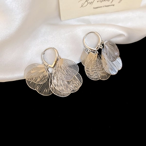 Détail macro de boucles d'oreilles pendantes en argent avec feuilles ajourées sur soie