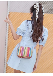 Detail of colorful woven straw crossbody camera bag with pink shoulder strap and zipper