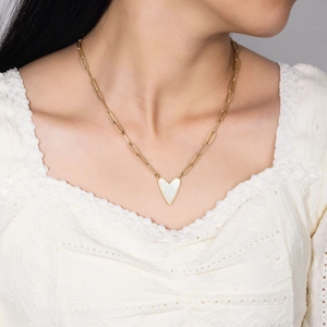 Close-up of golden titanium necklace with a white heart shell pendant on a model neck