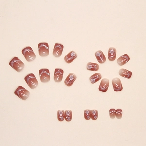 Pink gradient press-on nails with white floral patterns and pearl accents