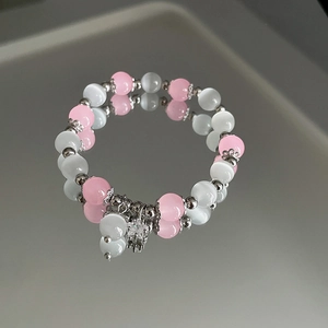 Makro-Detail von rosa-weißem Katzenaugen-Perlenarmband mit silbernem Sternanhänger