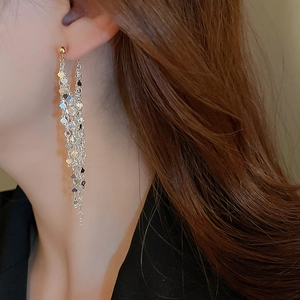 Close-up of long tassel earrings with silver chains and heart sequins on a model