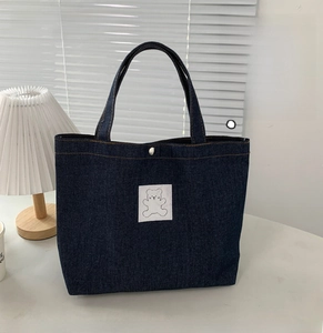 Close-up of dark blue denim tote bag featuring a cute white bear embroidery and metal buckle
