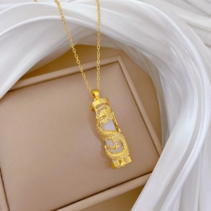 Macro detail of golden dragon pendant necklace on beige jewelry box with silk texture