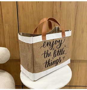 Dettaglio borsa tote in lino con manici in pelle e scritta enjoy the little things