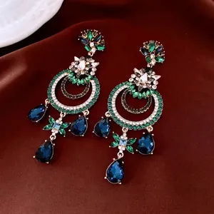 Boucles d'oreilles vintage dorées avec cristaux colorés sur fond en velours rouge