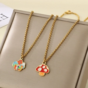 Detail of gold mushroom necklaces with colorful enamel charms on a textured jewelry box