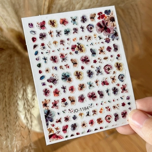 Detailed close-up of vintage flower nail art stickers with various floral patterns in purple and red