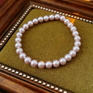 Close-up of pink purple pearl beads on green velvet pad with vintage wooden frame
