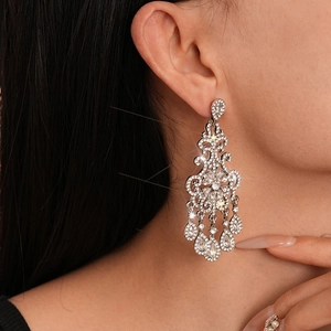 Close-up of sparkling chandelier earrings with teardrop tassels on female model