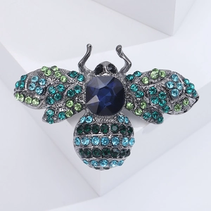 Macro shot of bee brooch with dark blue gemstones and colorful rhinestones on white stands