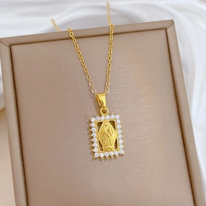 Detail of gold necklace featuring a rectangular frame with zircons and Mary pendant