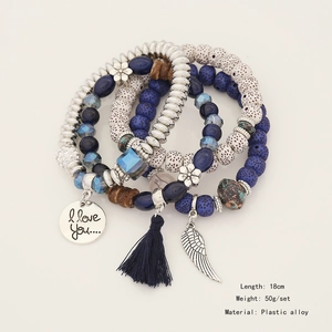 Close-up of bohemian beaded bracelet set featuring silver wing charms and tassel details