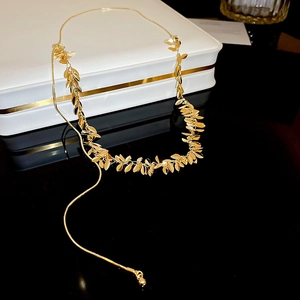 Dettaglio ravvicinato della collana con nappine dorate e pendenti a foglia su portagioie