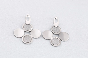 Détail des boucles d'oreilles géométriques en argent avec finitions mates et polies