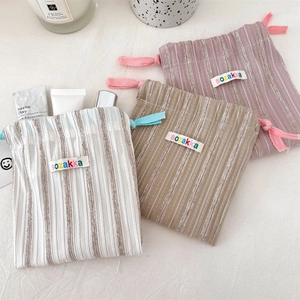 Detailed view of striped drawstring storage pouches with cotton embroidery and linen texture