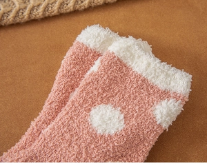 Close-up of thick pink coral fleece socks with white polka dots for winter warmth