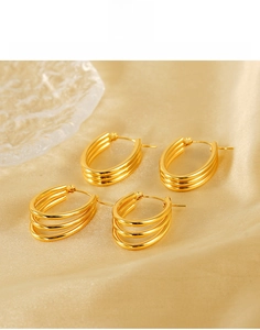 Detailed view of triple-layered 18k gold-plated titanium steel earrings on silk texture