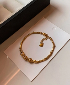 Detail of 18K gold plated bamboo link bracelet with zircon beads on a white card display