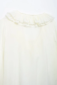 Detail of the ruffle V-neckline on a lightweight white chiffon blouse for women