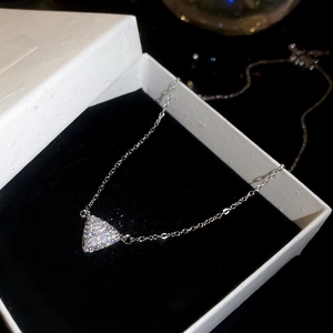 Vue macro d'un collier pendentif triangle en zircon argenté sur une boîte cadeau noire