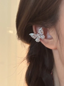 Detailed close-up of a silver butterfly ear cuff with sparkling zircons worn by a model