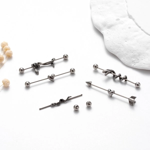 Detailed view of silver industrial barbell piercings with snake and heart designs