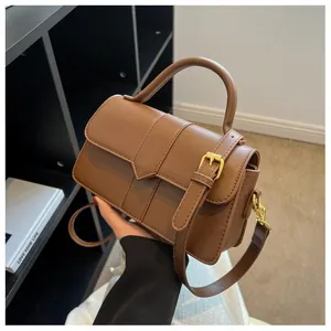Sac à main vintage en cuir PU marron avec bandoulière réglable tenu par un mannequin